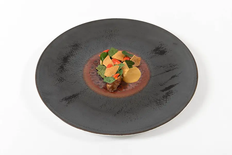 Contemporary dish with minimalist presentation and colorful ingredients, served at Osteria Francescana in Modena.